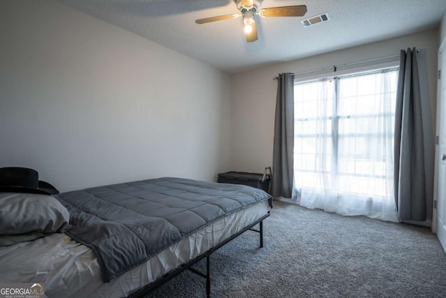 bedroom with ceiling fan, carpet floors, and a textured ceiling