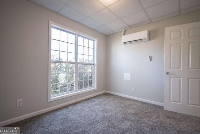 spare room with carpet, a drop ceiling, and a wall mounted AC