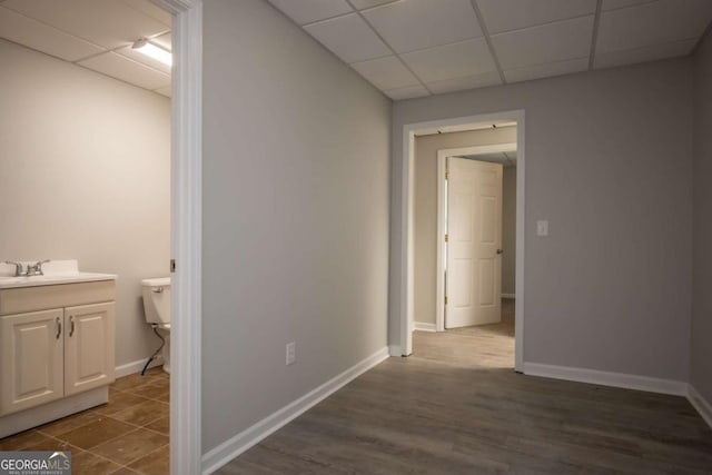 hallway with a paneled ceiling, dark hardwood / wood-style floors, and sink