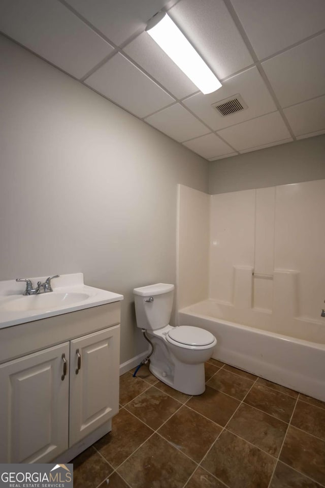 full bathroom with a paneled ceiling, vanity, toilet, and tile patterned flooring