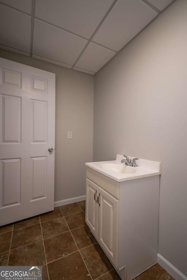 bathroom with tile patterned flooring, a drop ceiling, and vanity