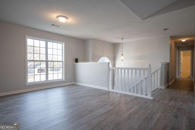 empty room with a textured ceiling and dark wood-type flooring