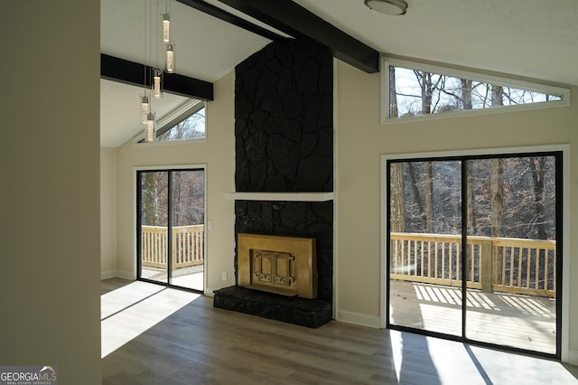 unfurnished living room with beam ceiling, a stone fireplace, high vaulted ceiling, and wood-type flooring