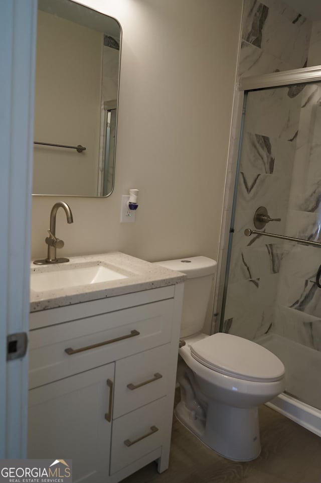 bathroom featuring hardwood / wood-style floors, vanity, toilet, and a shower with door