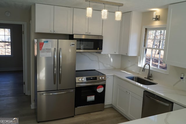 kitchen featuring white cabinetry, sink, pendant lighting, and appliances with stainless steel finishes