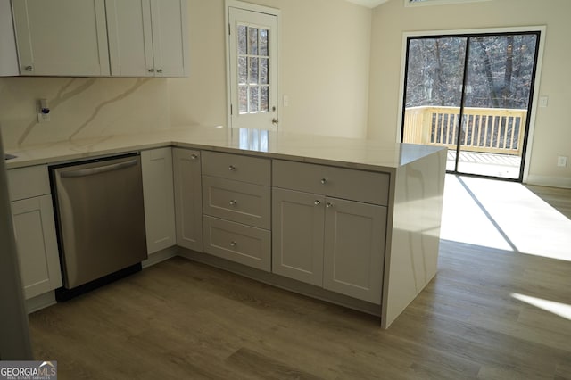 kitchen featuring backsplash, kitchen peninsula, light stone countertops, and dishwasher