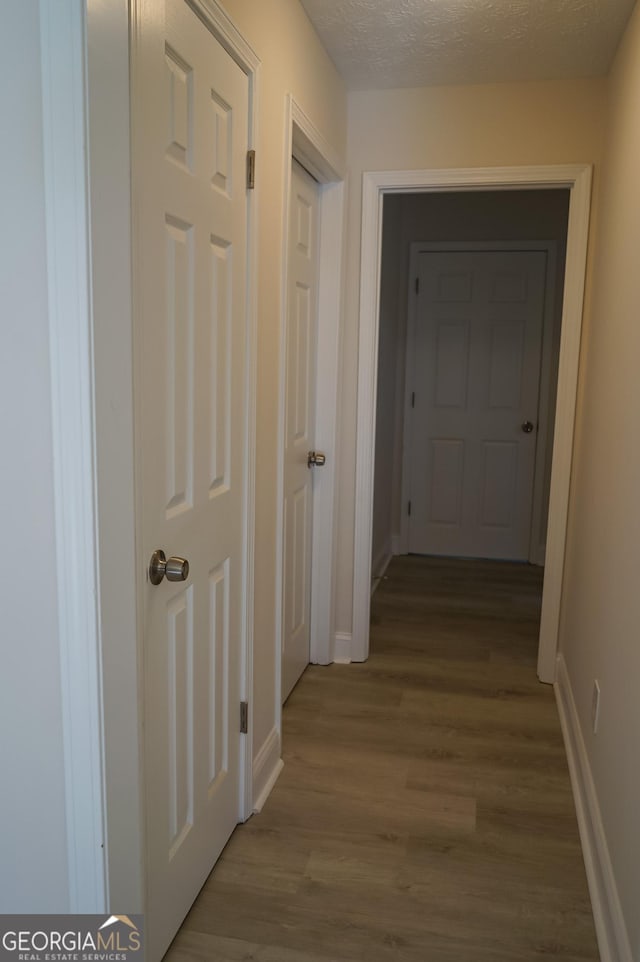 hallway with a textured ceiling and light hardwood / wood-style floors