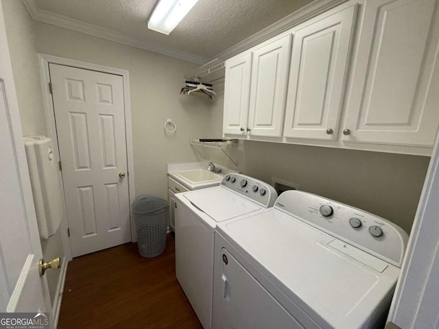 laundry room featuring sink, cabinets, a textured ceiling, dark hardwood / wood-style flooring, and washer and clothes dryer