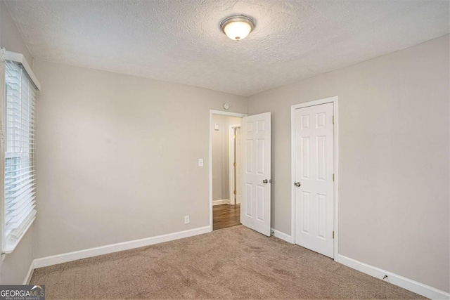 unfurnished bedroom with a closet, carpet floors, a textured ceiling, and multiple windows