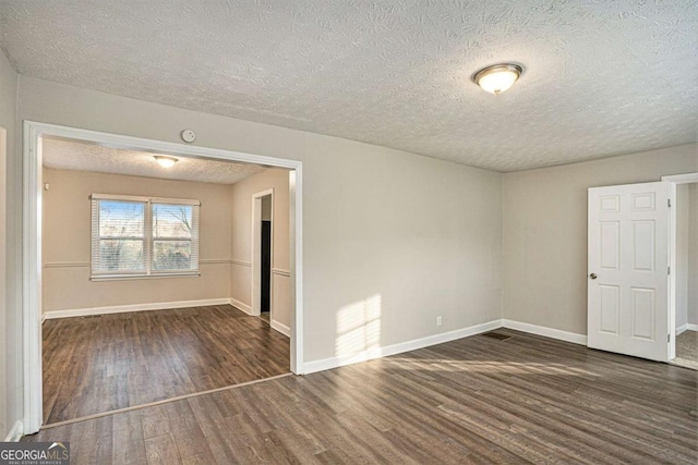 spare room featuring dark hardwood / wood-style flooring and a textured ceiling