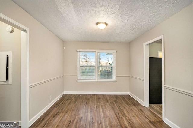 unfurnished dining area with dark wood-type flooring and a textured ceiling