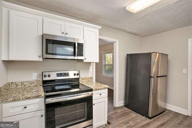 kitchen featuring light stone countertops, dark hardwood / wood-style flooring, white cabinets, and appliances with stainless steel finishes