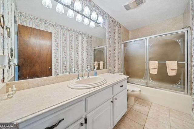 full bathroom featuring vanity, combined bath / shower with glass door, tile patterned flooring, toilet, and a textured ceiling