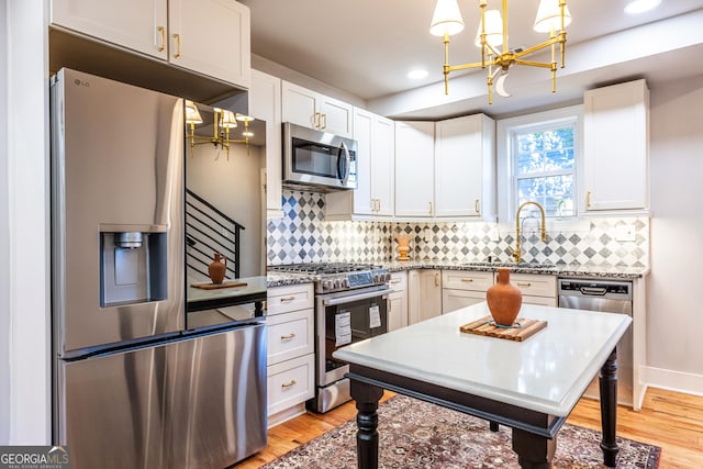 kitchen with decorative light fixtures, stainless steel appliances, white cabinetry, and sink