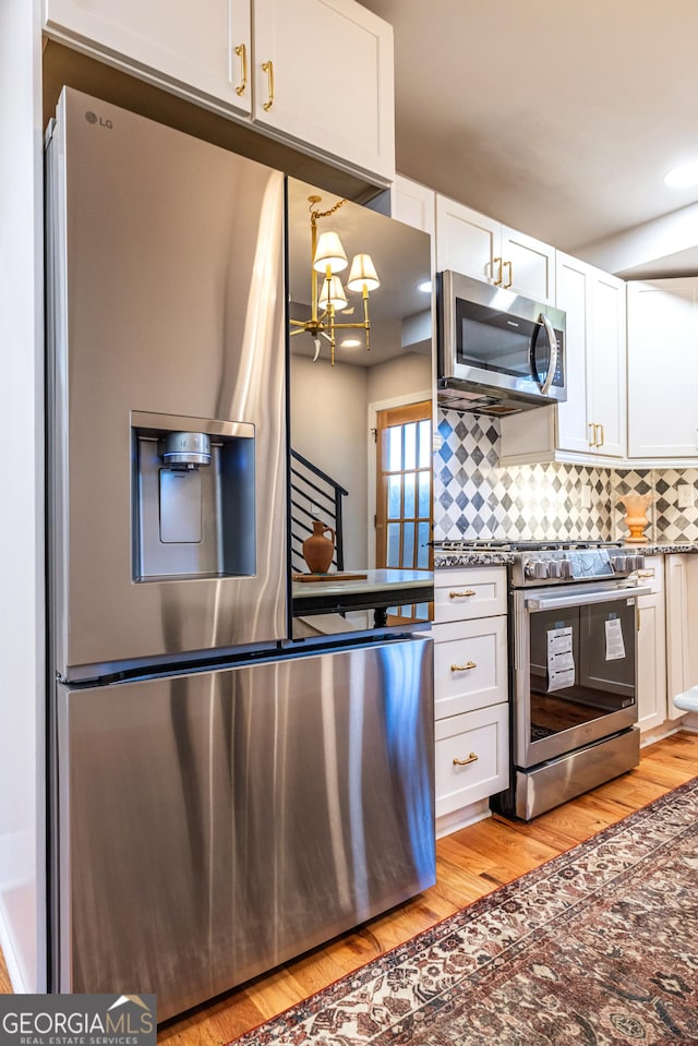 kitchen featuring white cabinetry, tasteful backsplash, light hardwood / wood-style flooring, a chandelier, and appliances with stainless steel finishes