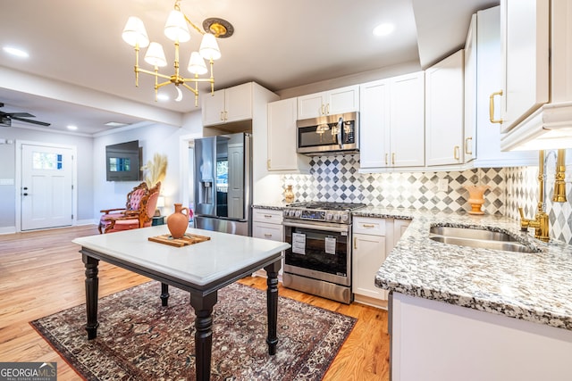 kitchen featuring sink, white cabinetry, stainless steel appliances, and hanging light fixtures