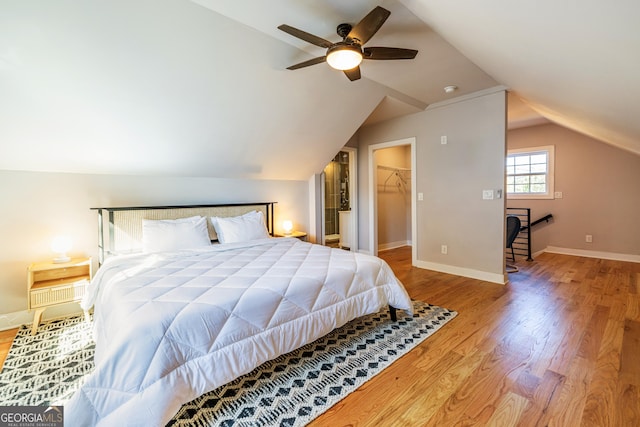 bedroom featuring a walk in closet, vaulted ceiling, ceiling fan, hardwood / wood-style floors, and a closet