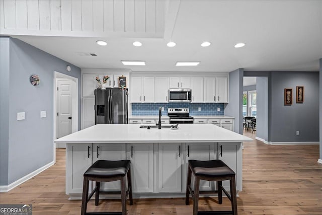 kitchen with sink, appliances with stainless steel finishes, a kitchen breakfast bar, and a kitchen island with sink