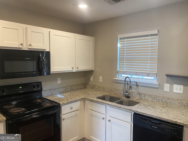 kitchen with black appliances, white cabinetry, and a sink