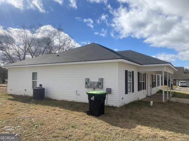 view of property exterior featuring roof with shingles, cooling unit, and a yard