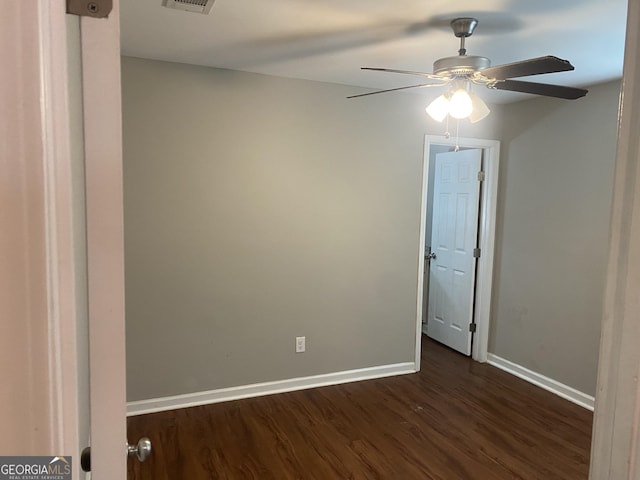 unfurnished room featuring visible vents, dark wood-type flooring, a ceiling fan, and baseboards