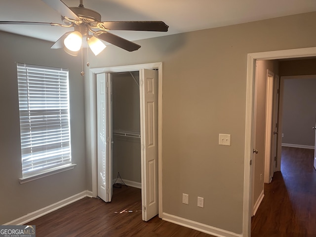 unfurnished bedroom featuring dark wood-style floors, ceiling fan, a closet, and baseboards