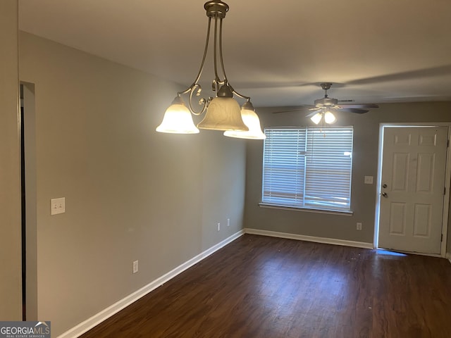 unfurnished dining area featuring baseboards, dark wood finished floors, and a ceiling fan