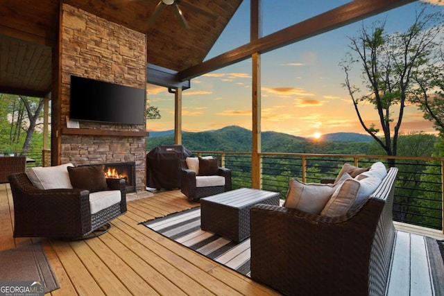 wooden deck featuring an outdoor living space with a fireplace, ceiling fan, and a grill