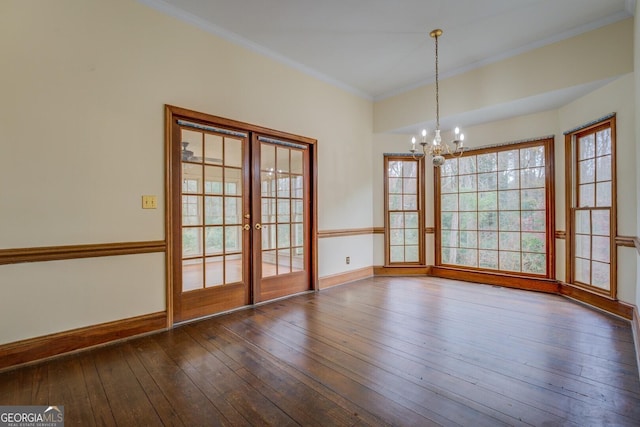 unfurnished room with french doors, hardwood / wood-style flooring, crown molding, and a notable chandelier