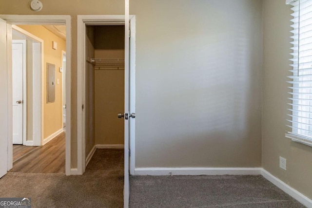 unfurnished bedroom featuring carpet flooring, electric panel, and a closet