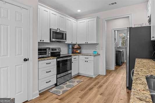 kitchen featuring a toaster, visible vents, light stone counters, stainless steel appliances, and white cabinetry