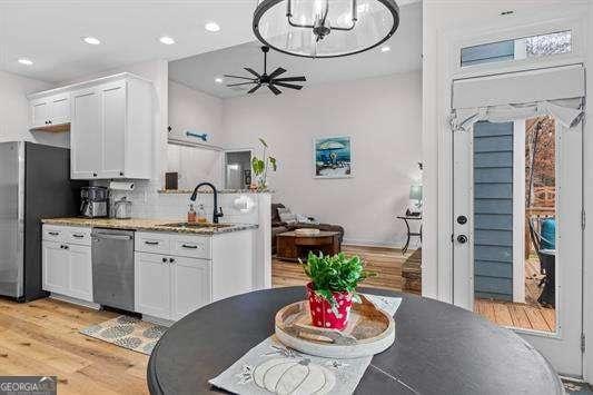 kitchen with freestanding refrigerator, white cabinetry, a sink, and stainless steel dishwasher