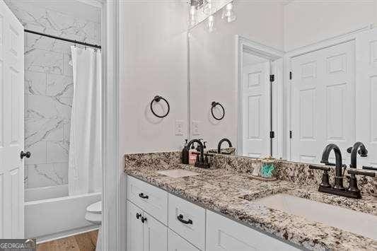 bathroom with wood finished floors, double vanity, shower / bath combination with curtain, and a sink