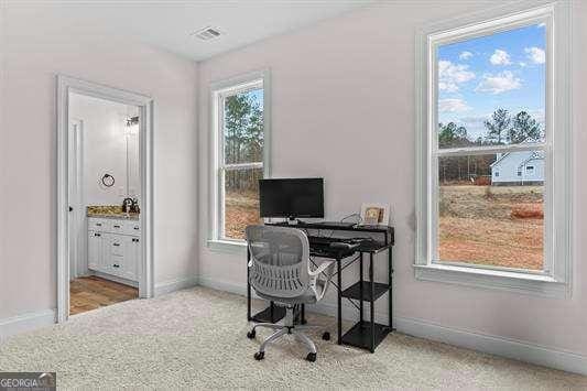 office featuring baseboards, visible vents, a wealth of natural light, and carpet flooring