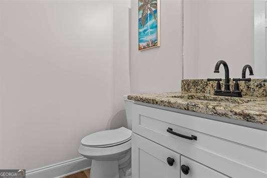 bathroom featuring toilet, baseboards, and vanity