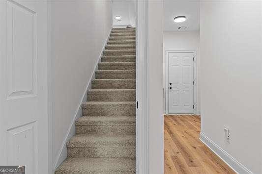 staircase featuring wood finished floors and baseboards