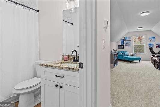 full bath with lofted ceiling, a shower with shower curtain, vanity, and toilet