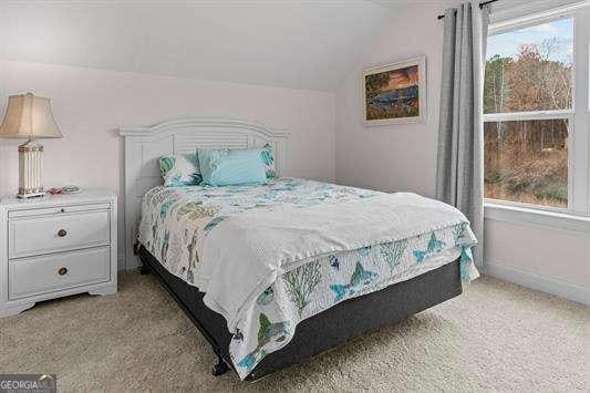 bedroom with multiple windows, vaulted ceiling, light carpet, and baseboards