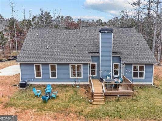 back of house with a shingled roof, a wooden deck, a chimney, a yard, and central air condition unit