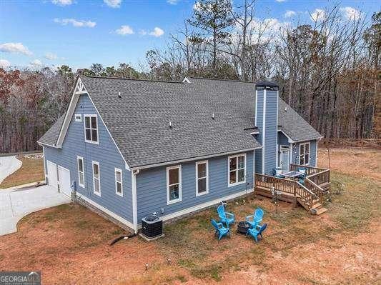 back of property featuring an outdoor fire pit, a chimney, roof with shingles, a deck, and central air condition unit