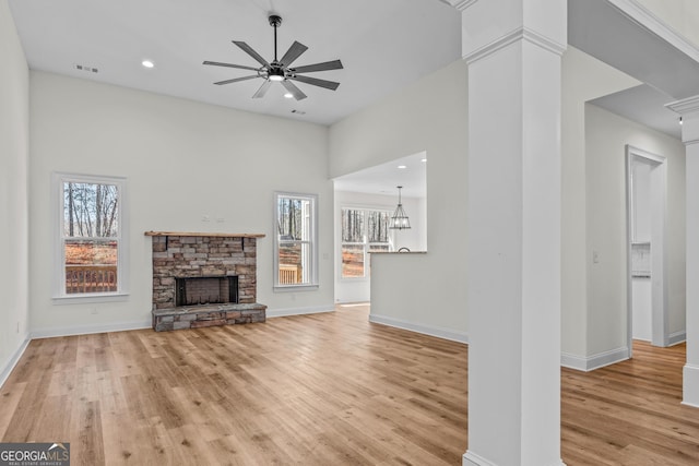 unfurnished living room featuring ceiling fan, a fireplace, visible vents, baseboards, and light wood finished floors