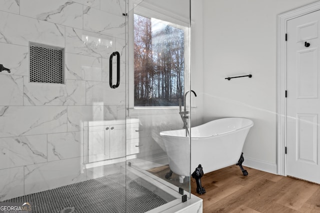 bathroom featuring a freestanding bath, wood finished floors, a shower stall, and baseboards