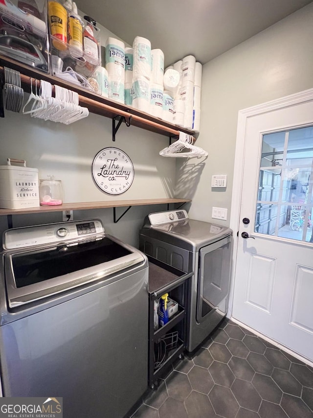 laundry room featuring washing machine and dryer and dark tile patterned flooring