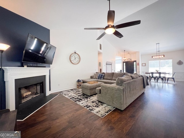 living room with dark hardwood / wood-style flooring, ceiling fan with notable chandelier, and vaulted ceiling