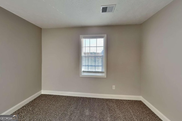 unfurnished room with carpet flooring and a textured ceiling