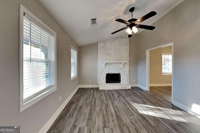 unfurnished living room with a fireplace, light hardwood / wood-style flooring, vaulted ceiling, and ceiling fan