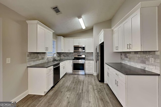 kitchen with white cabinets, lofted ceiling, sink, and appliances with stainless steel finishes