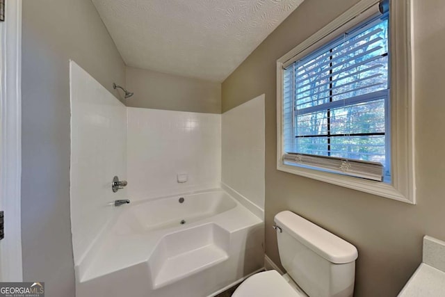 bathroom featuring washtub / shower combination, a textured ceiling, and toilet