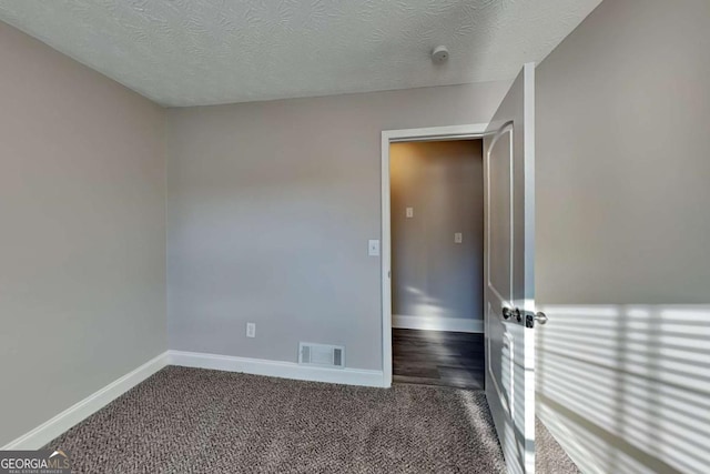 empty room featuring dark colored carpet and a textured ceiling