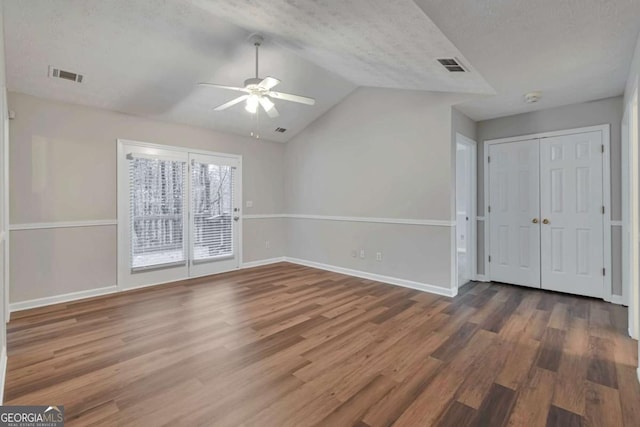 spare room with a textured ceiling, vaulted ceiling, ceiling fan, and dark wood-type flooring